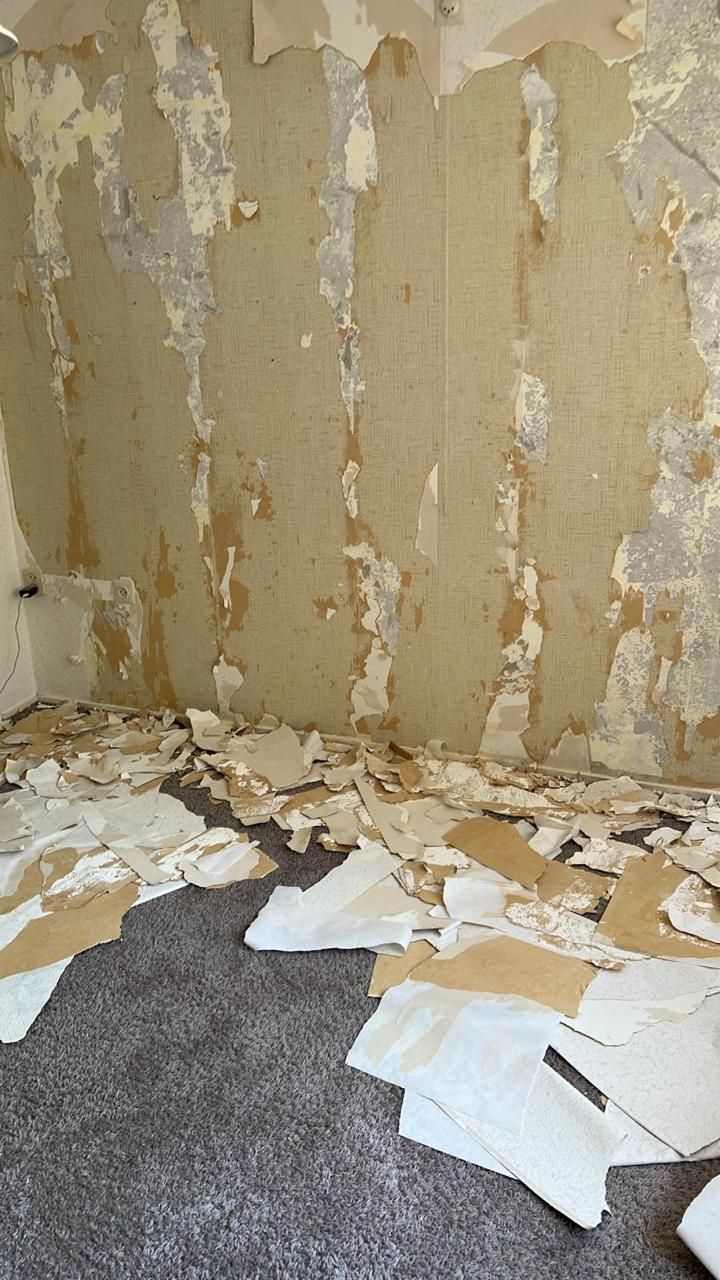 Woonkamerwand met verwijderd behang en resten op de vloer