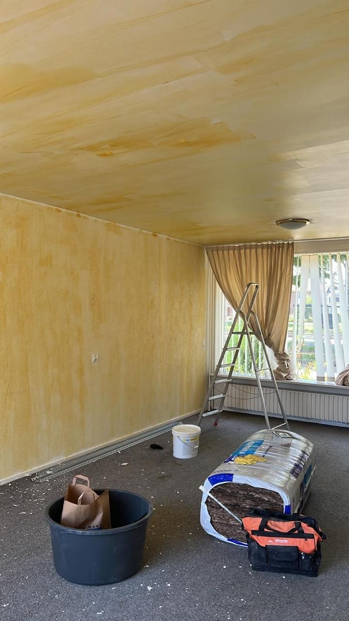Voorkamer met gele wanden en plafond, ladder en isolatierol