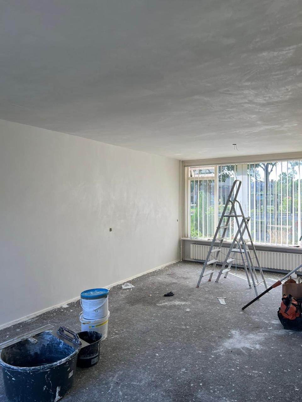 Afgewerkte woonkamer met vlakke witte wanden en plafond