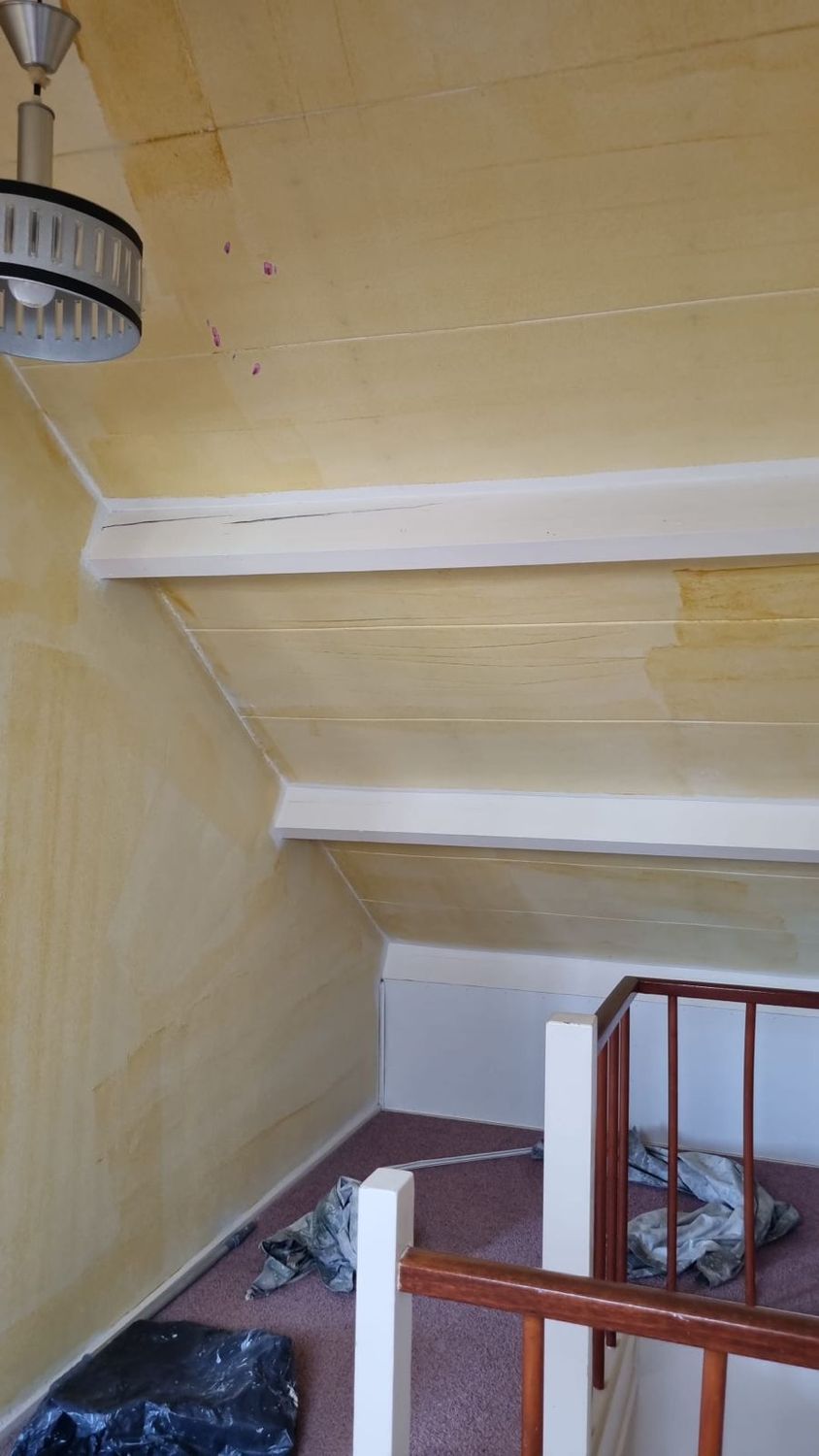 Zolderoverloop met gele schuine plafonds en witte balken