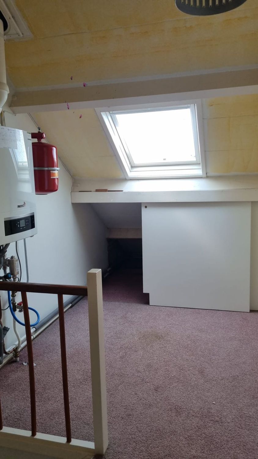 Zolderkamer met dakraam en cv-ketel aan de wand
