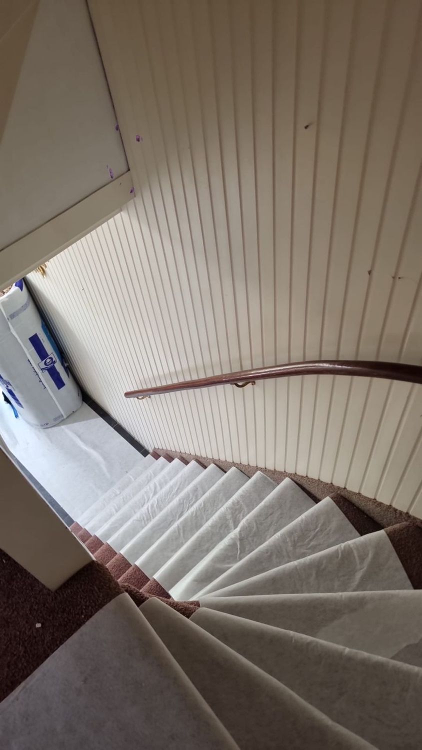 Zicht op de afgedekte trap met houten leuning