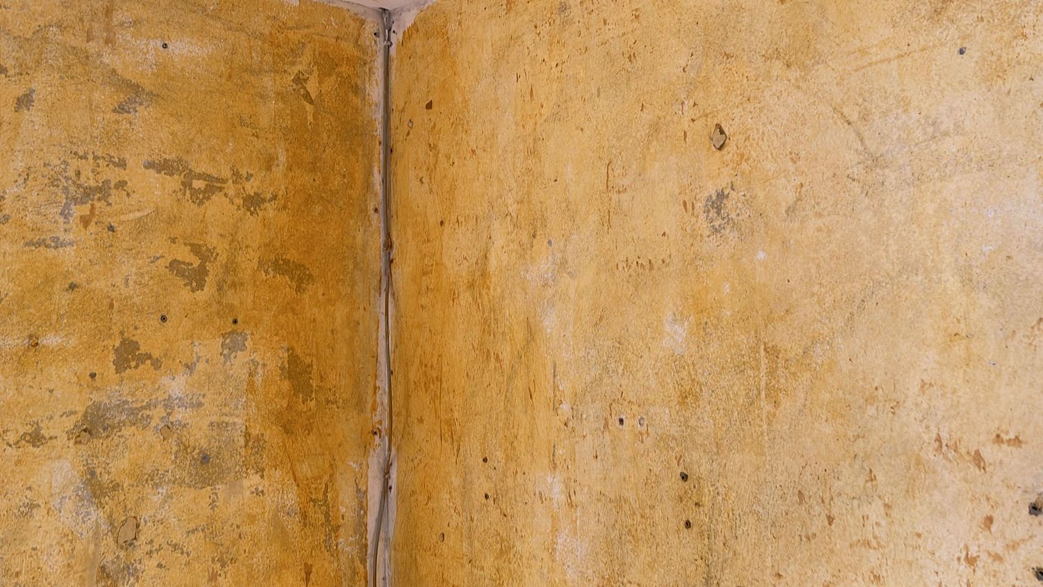 Close-up van een wandhoek met gele lijmresten
